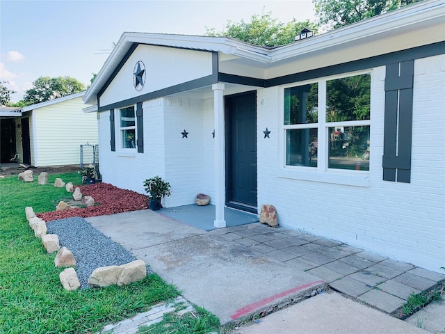 entrance to property featuring a patio area and brick siding