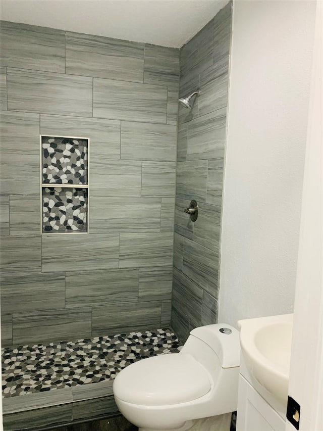 full bath featuring vanity, toilet, and tiled shower