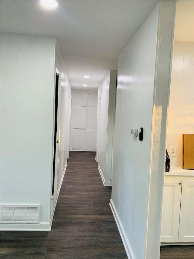 corridor with dark wood finished floors, visible vents, and baseboards
