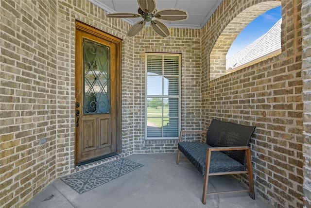 view of exterior entry with brick siding and a ceiling fan
