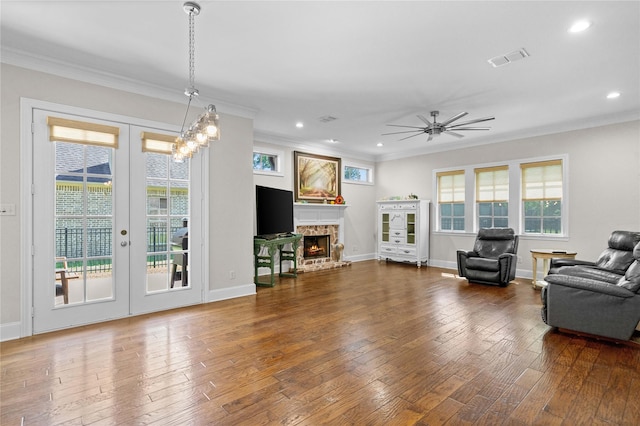 living room with visible vents, plenty of natural light, crown molding, and a stone fireplace