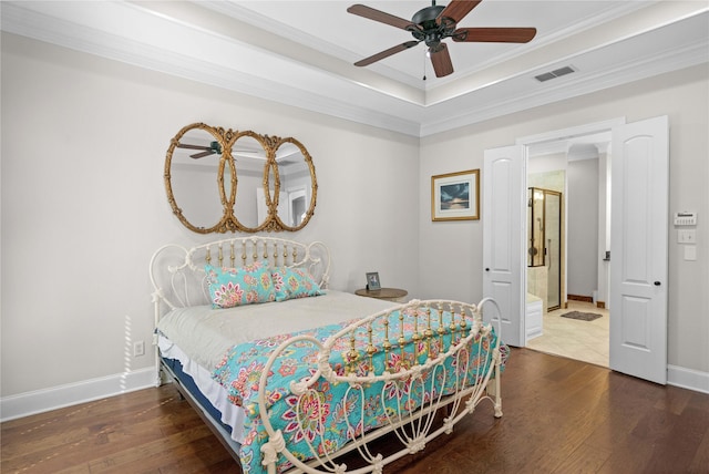 bedroom featuring a tray ceiling, visible vents, baseboards, ornamental molding, and hardwood / wood-style flooring