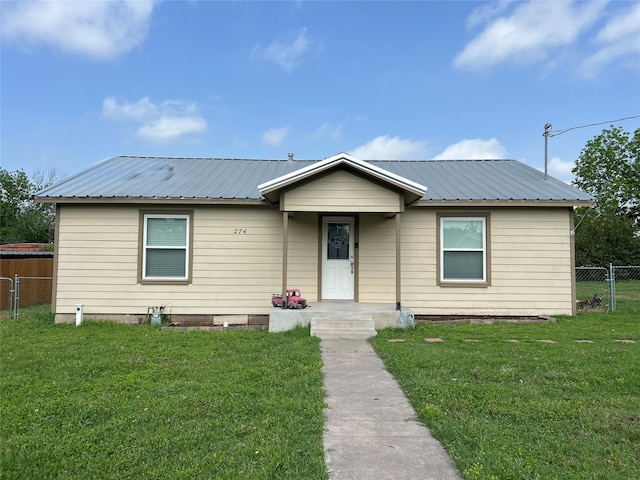 view of front of property featuring fence, metal roof, and a front lawn