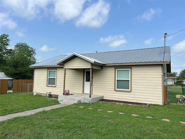 view of front of property featuring fence, metal roof, and a front yard
