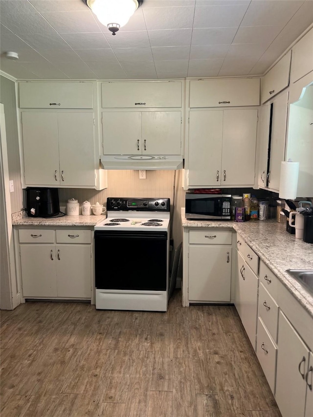 kitchen with stainless steel microwave, light countertops, under cabinet range hood, electric range, and wood finished floors