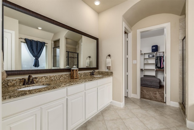 bathroom featuring a sink, a stall shower, double vanity, and a spacious closet