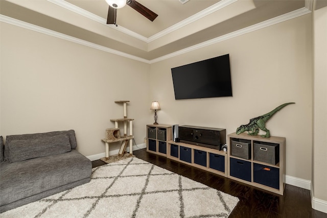 living area with crown molding, a ceiling fan, baseboards, and wood finished floors