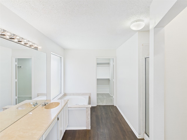1117 Victoria Dr, Saginaw, TX 76131 - bathroom with a spacious closet, wood finished floors, a textured ceiling, and a bath