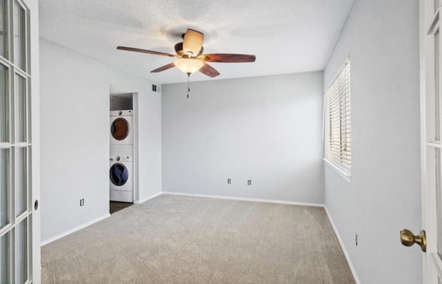 interior space with carpet floors, a ceiling fan, stacked washing maching and dryer, and visible vents