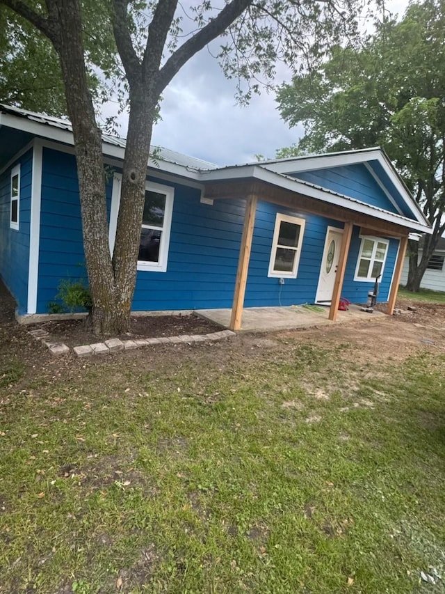 view of front of house featuring a porch, metal roof, and a front yard
