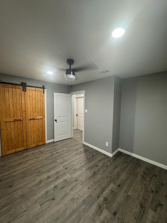 unfurnished bedroom with baseboards, visible vents, a ceiling fan, and dark wood finished floors