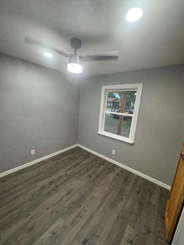 spare room featuring baseboards and dark wood-style flooring