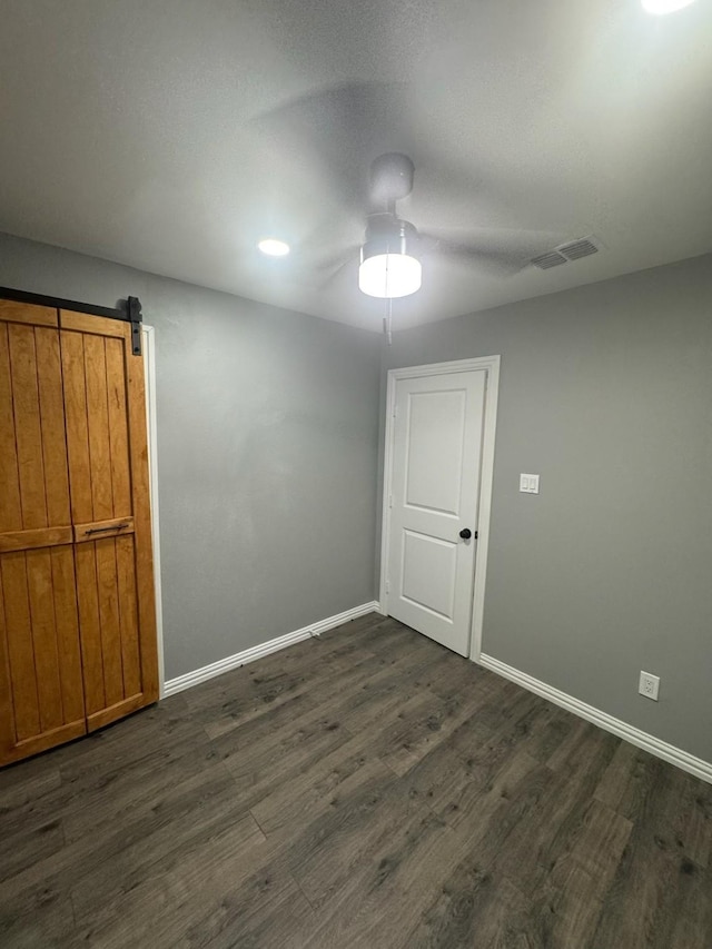 spare room with dark wood-type flooring, visible vents, and baseboards