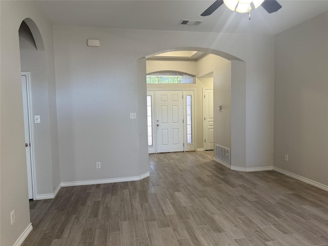 entrance foyer featuring visible vents, wood finished floors, a ceiling fan, and arched walkways