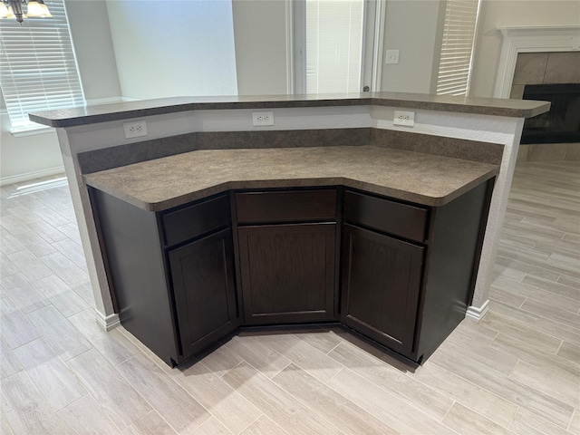 kitchen featuring wood tiled floor, dark countertops, and a tiled fireplace