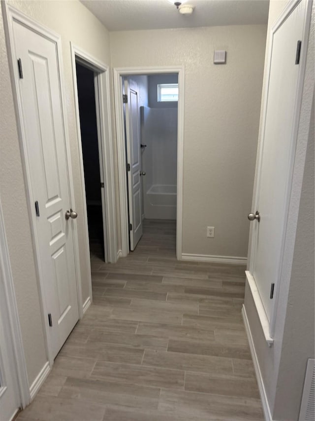 corridor with light wood-style flooring and baseboards