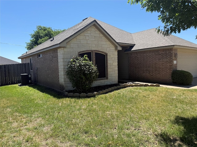 exterior space with a lawn, an attached garage, brick siding, and fence