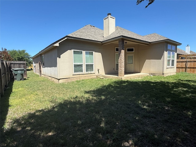 back of property with fence, a yard, and a patio area