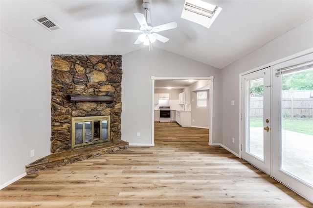 1601 Winderemere Dr, Arlington, TX 76014 - unfurnished living room with a ceiling fan, a stone fireplace, visible vents, wood finished floors, and lofted ceiling with skylight