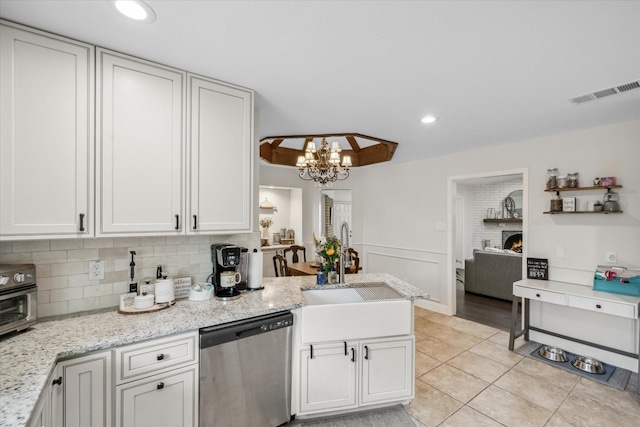 kitchen with a sink, an inviting chandelier, light tile patterned floors, visible vents, and stainless steel dishwasher