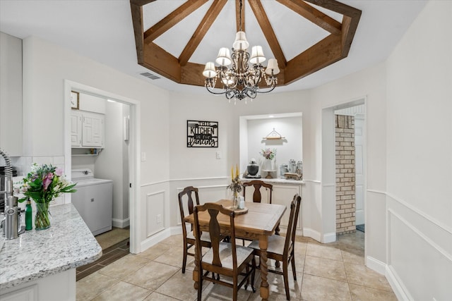 dining area featuring light tile patterned floors, visible vents, beam ceiling, washer / dryer, and a notable chandelier