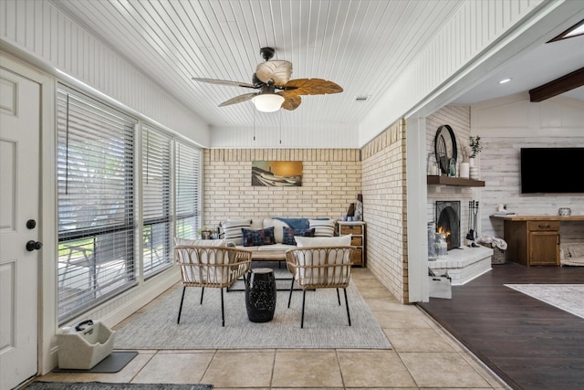 tiled dining area with a brick fireplace, visible vents, ceiling fan, and brick wall
