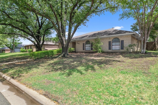 ranch-style house with a front yard and brick siding