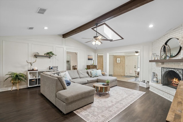 living area with a fireplace, ceiling fan, lofted ceiling with beams, and visible vents