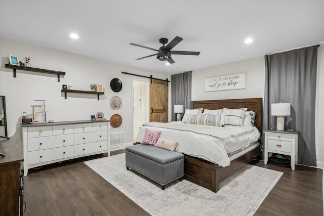 bedroom with a barn door, visible vents, dark wood-style flooring, recessed lighting, and a ceiling fan