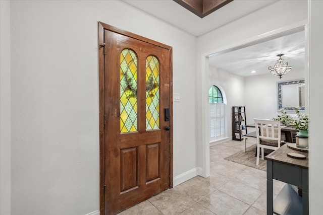 foyer with light tile patterned floors, a chandelier, and baseboards