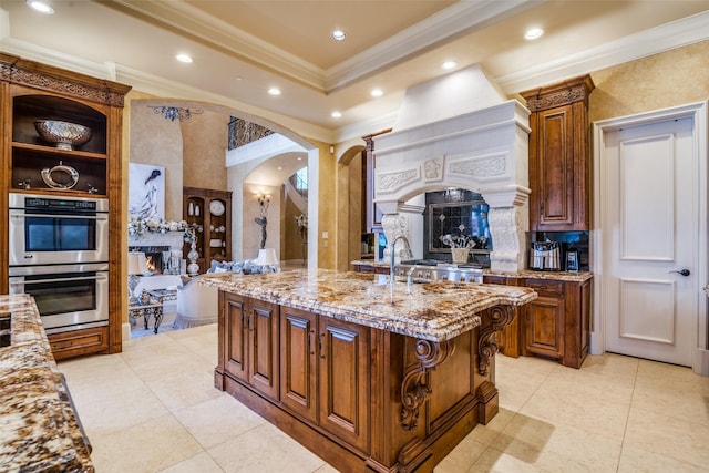 kitchen featuring ornamental molding, a fireplace, stainless steel double oven, light stone counters, and arched walkways