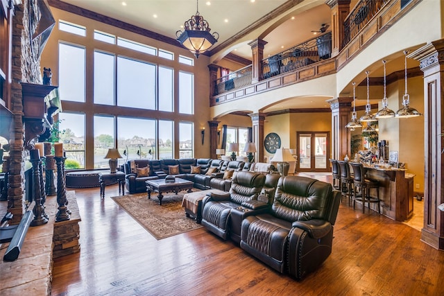 living area featuring crown molding, decorative columns, a high ceiling, recessed lighting, and arched walkways