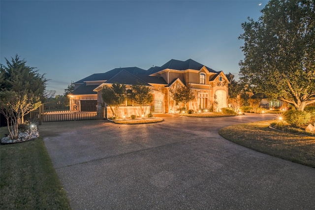 view of front of home with curved driveway, a gate, and stucco siding