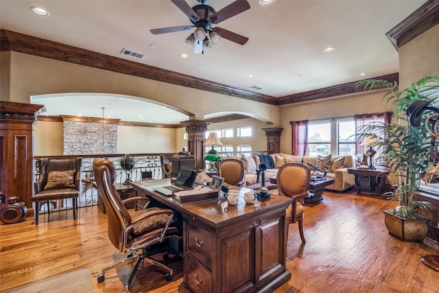 office space with arched walkways, a ceiling fan, ornate columns, visible vents, and ornamental molding