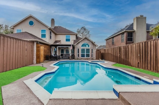 rear view of house with a patio, an in ground hot tub, a fenced in pool, brick siding, and a fenced backyard