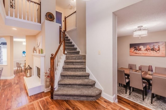 stairway featuring baseboards, wood finished floors, and arched walkways