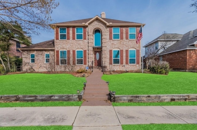 view of front facade featuring a front yard, brick siding, and a chimney