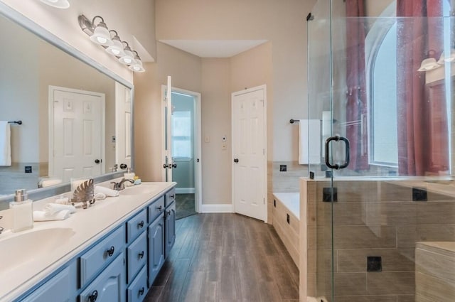 bathroom with double vanity, wood finished floors, a shower stall, and a sink