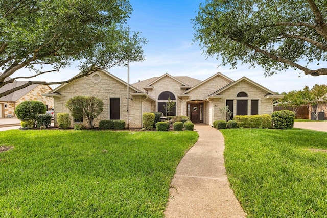 ranch-style home with fence, a front lawn, and stone siding