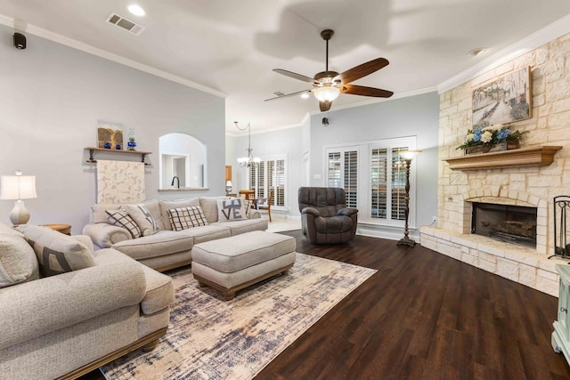 living area with wood finished floors, ornamental molding, ceiling fan with notable chandelier, a fireplace, and visible vents