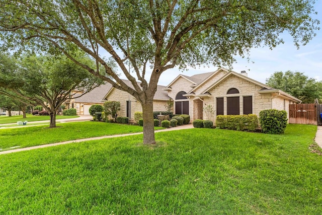 single story home with fence, a front yard, and stone siding