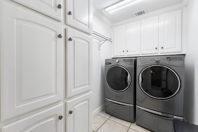 washroom featuring cabinet space, light tile patterned flooring, separate washer and dryer, visible vents, and baseboards