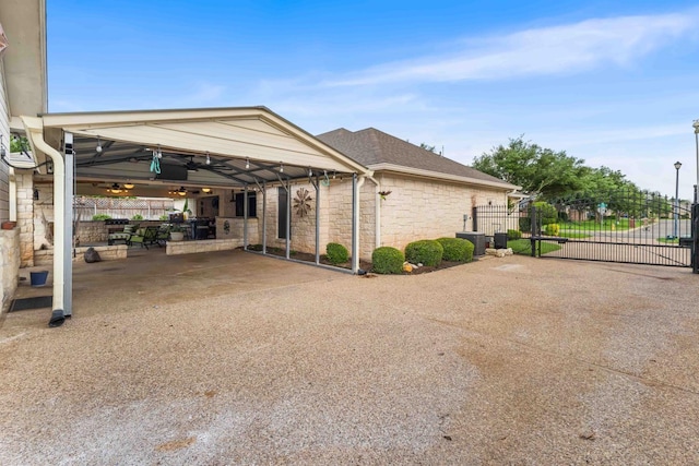 exterior space with driveway, fence, a gate, and stone siding