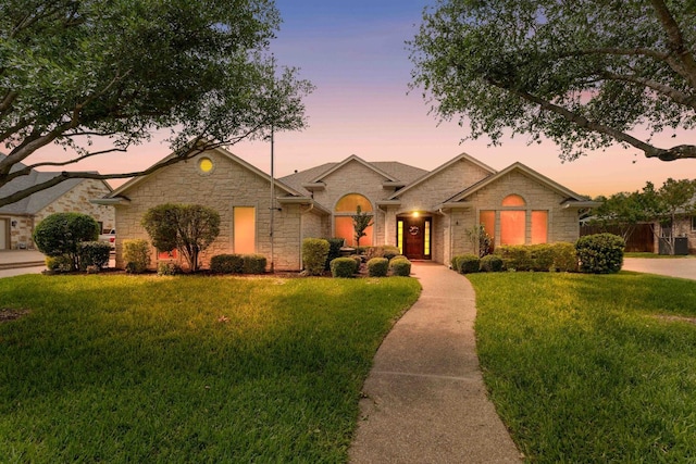 single story home featuring a front lawn, stone siding, and fence