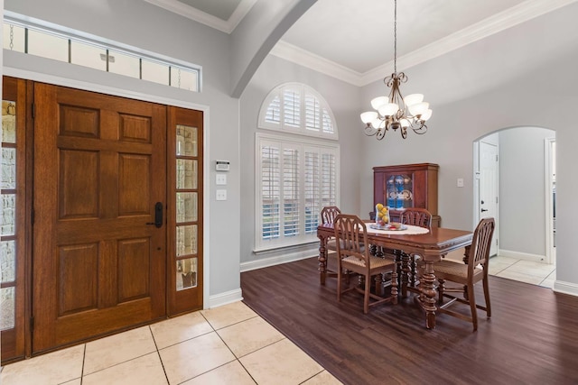 dining area featuring light tile patterned floors, arched walkways, a notable chandelier, and ornamental molding