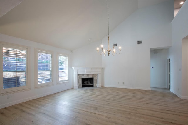 unfurnished living room featuring visible vents, an inviting chandelier, baseboards, light wood-type flooring, and high vaulted ceiling