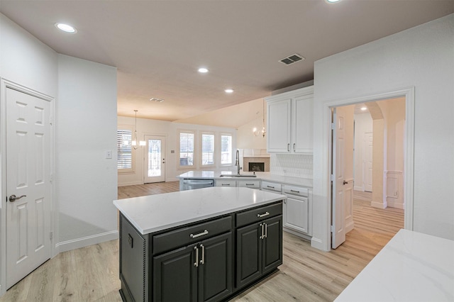 kitchen featuring light wood finished floors, visible vents, stainless steel dishwasher, and white cabinets