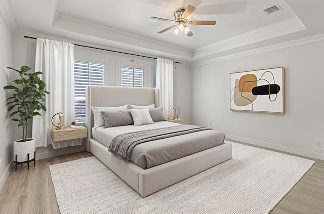 bedroom featuring ornamental molding, wood finished floors, a raised ceiling, and visible vents