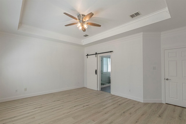 empty room with visible vents, ceiling fan, light wood-type flooring, a raised ceiling, and crown molding