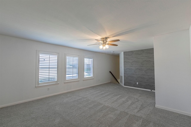 carpeted spare room with visible vents, a ceiling fan, and baseboards